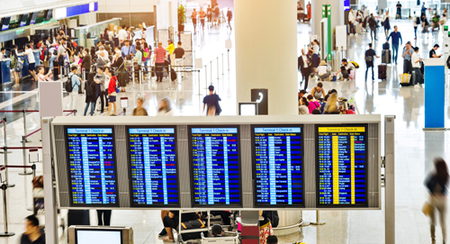 busy airline terminal with digital monitors and check-in stations