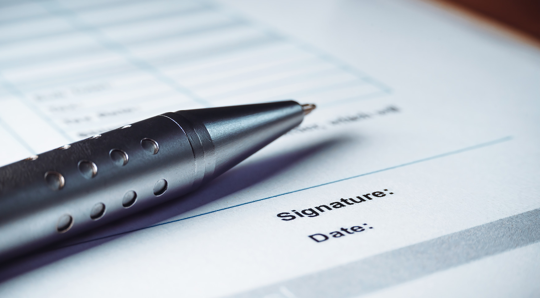 Close up of a pen sitting on legal documents for signature and date