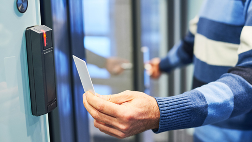 hand holding security card to card reader for access to office