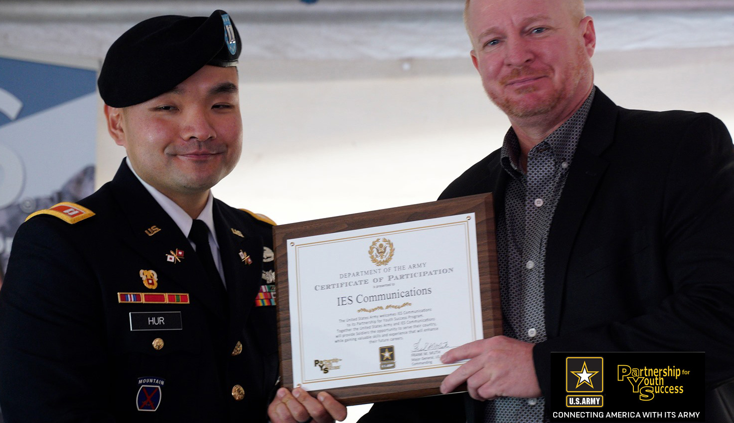 IES Communications executive receives a certificate from a US Army official for participation in the US Army Partnership for Youth Success program